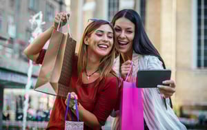 Due clienti con borse della spesa scattano un selfie.