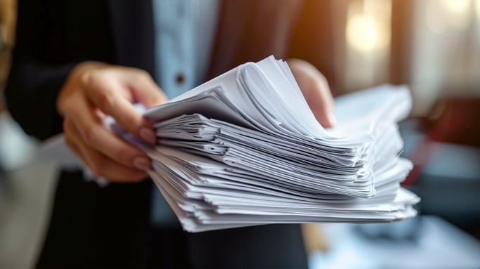 persona che tiene in mano una pila di fogli burocratici