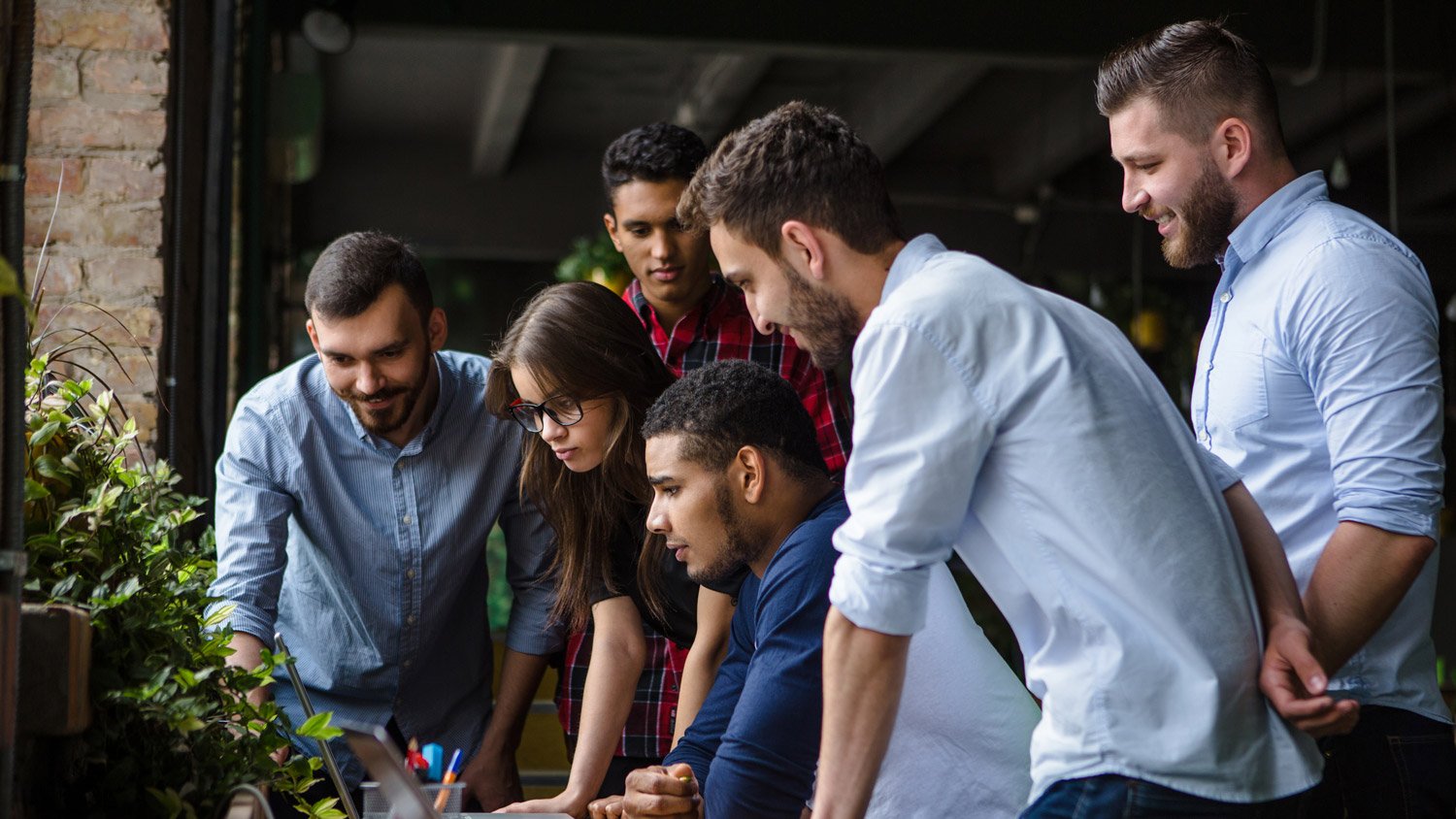 Il team Novatag riunito attorno a un laptop mentre discute e analizza insieme strategie e soluzioni per campagne e progetti digitali.